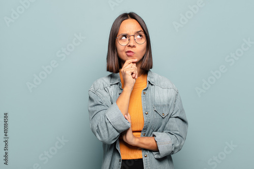 Принти на полотні young hispanic woman thinking, feeling doubtful and confused, with different opt