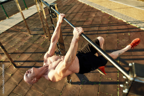Muscular caucasian sportsman hanging horizontally on crossbar