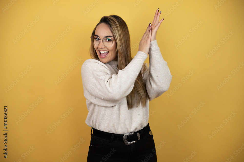 Pretty woman with long hair clapping and applauding happy and joyful, smiling proud hands together against yellow wall Pretty woman with long hair clapping and applauding happy and joyful, smiling proud hands together against yellow wall