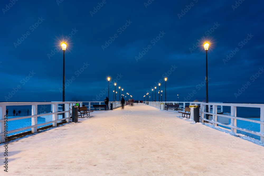 Illuminated pier in Brzezno on the winter beach at dusk, Gdansk.  Poland.