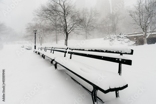 Central Park snow. Historic architecture in New York City Central Park. Beautiful bow bridge in Manhattan Central Park with snow flakes. Winter in NYC. Blizzard in New York City. 