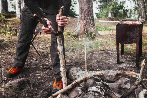 Man prepares tourist campfire. Hands in the frame put a tree for a fire
