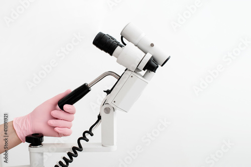 woman gynecologist in pink gloves working with colposcope in clinic  on white background. Copy space photo