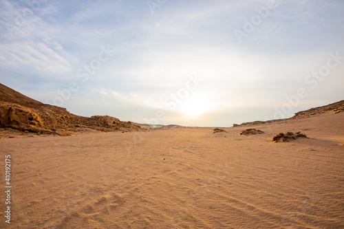 sand dunes and stones in the desert of Egypt at sunset with blue sky