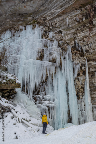 Hiker near frozen Awosting Falls, massive icicles hang from the cliffs in Minnewaska State Park in Upstate New York. USA photo