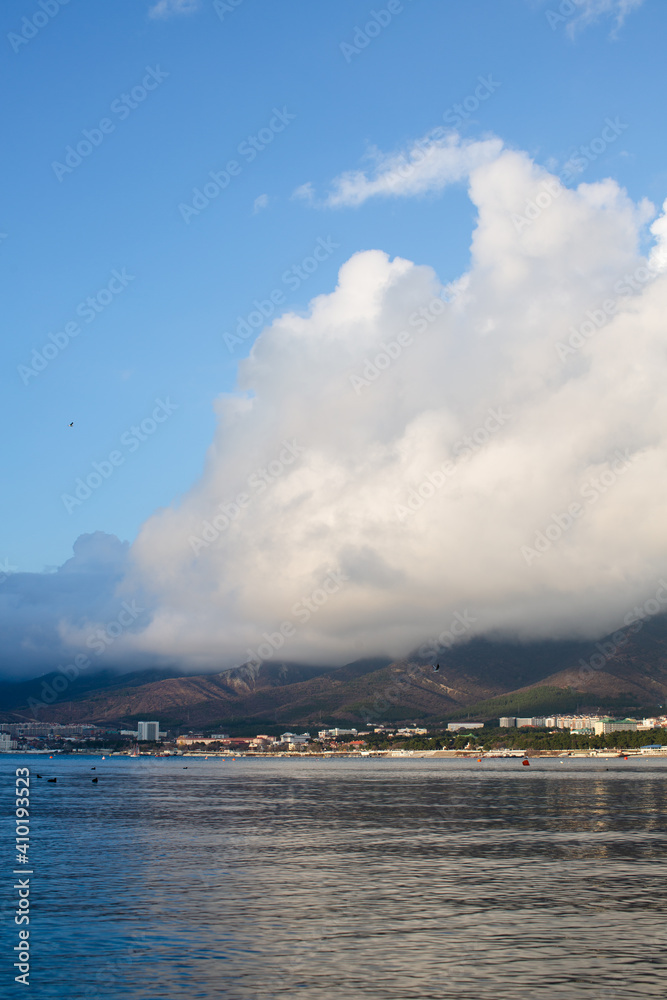 A huge white cloud over the sea and mountains