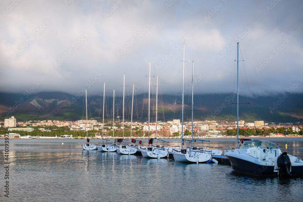 White yachts stand on the shore with a view of the mountains