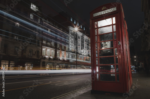 Photography A classic London telephone box at night as double decker bus drives by leaving behind light trails