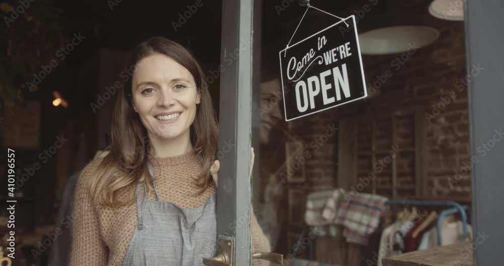 Portrait of female shop owner looking at camera after turning open sign