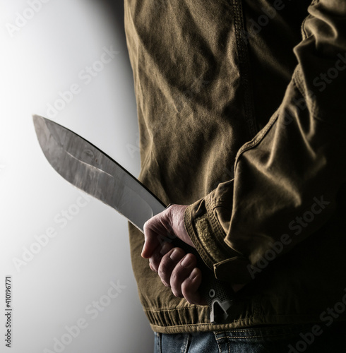 Man holding a machete behind his back