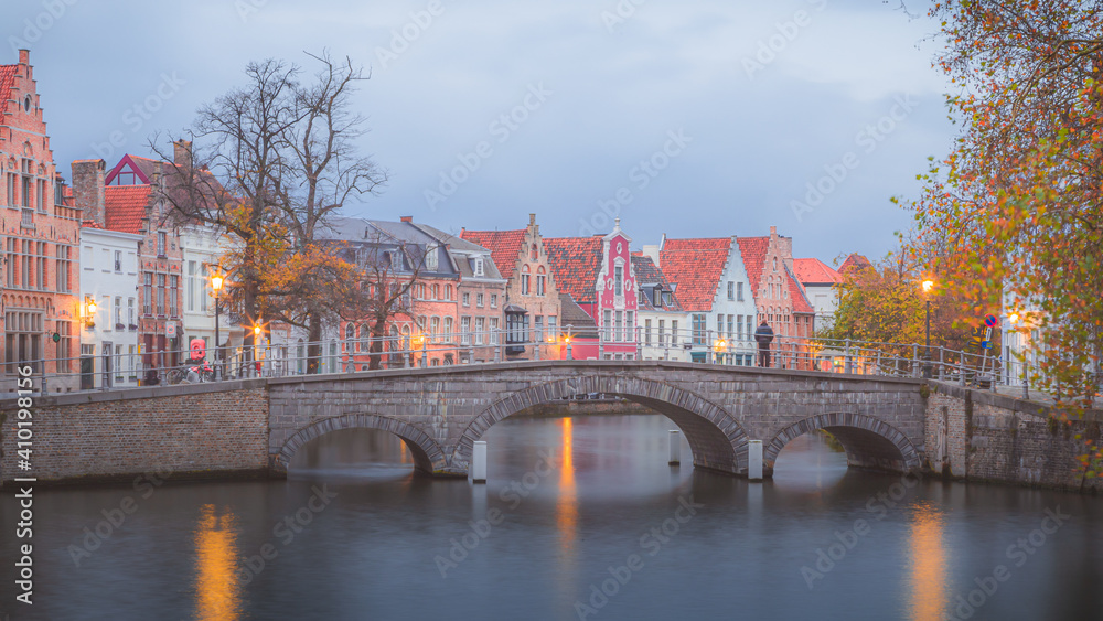 A man stands on his own on Carmers Bridge in the beautiful old town of Bruges, Belgium at dusk.