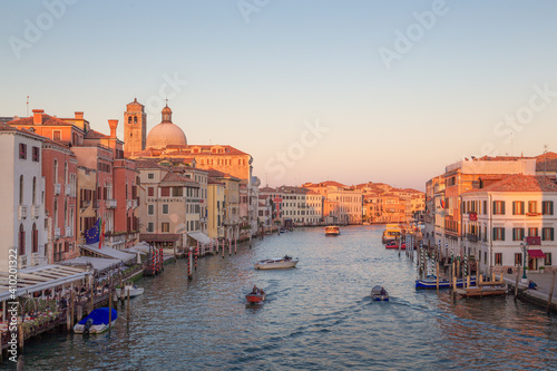 Evening golden light on the bustling iconic tourist attraction Grand Canal in Venice, Italy.
