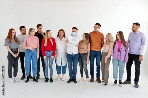 sick male feels constrained and uncomfortable among healthy people, afraid of infecting someone, group of people look at him, isolated over white background