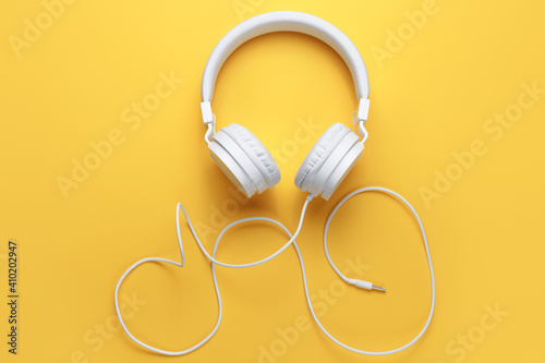 Photo of white headphone on yellow background. Music concept.