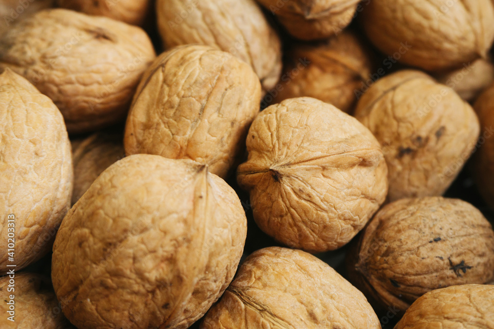 Walnut background. Natural walnuts texture. Nuts in shells. Stacked pile of wallnuts pattern. Walnut background. Natural walnuts texture. Nuts in shells. Stacked pile of wallnuts pattern.
