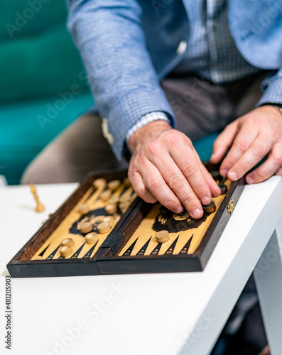 Vintage wooden backgammon pattern and the dice in the front view. Man`s hand moving dibs.