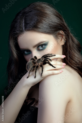girl brunette green make up eyes gaze on black background close up portrait with brown spider on face tarantula