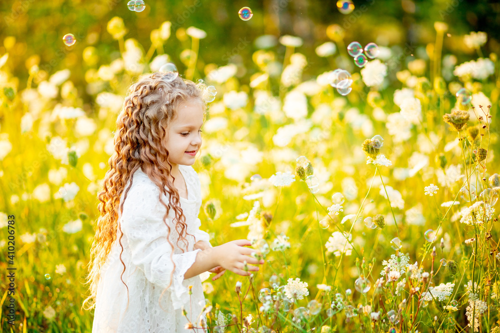 little beautiful girl playing on the lawn in summer with soap bubbles little beautiful girl playing on the lawn in summer with soap bubbles