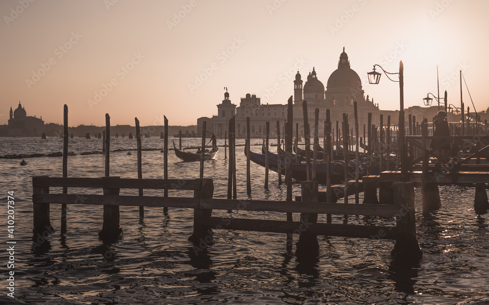 Golden hour in Venice as a gondolier navigates the Grand Canal with tourists on his gondola at sunset in Italy.