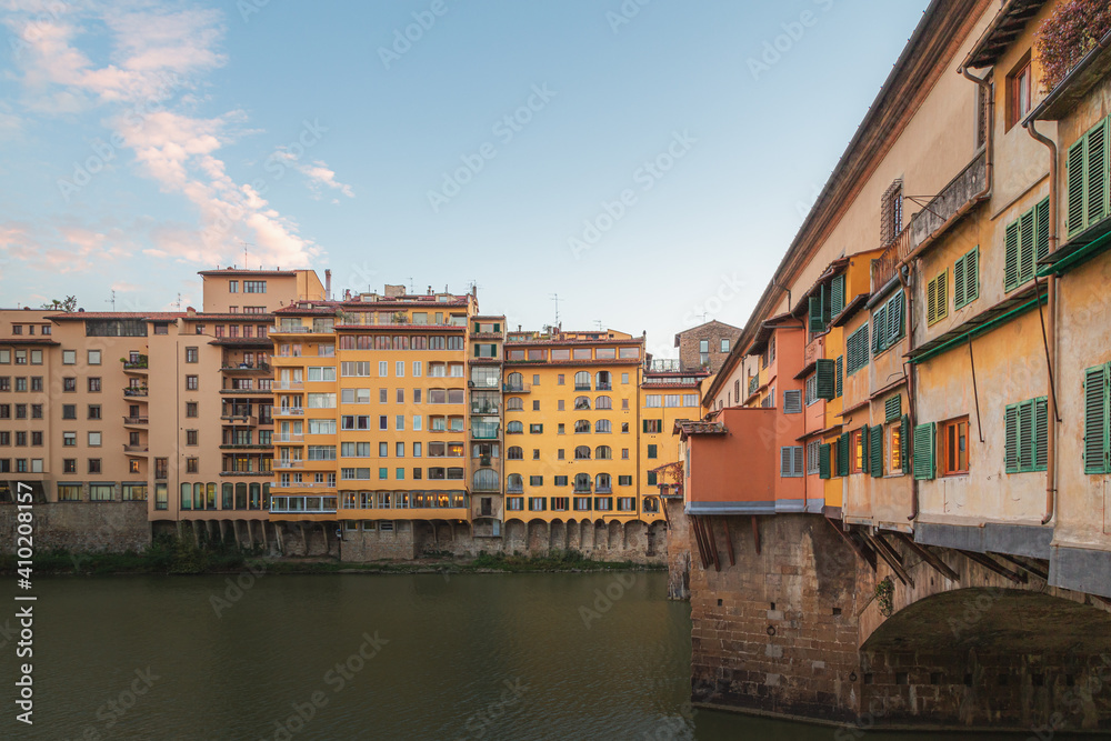 The historic and popular tourist attraction Ponte Vecchio bridge perched over the River Arno in Florence, Italy on a clear sunny day in Tuscany.