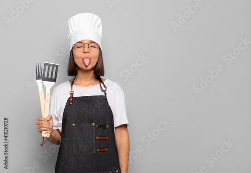 young hispanic woman with cheerful, carefree, rebellious attitude, joking and sticking tongue out, having fun photo