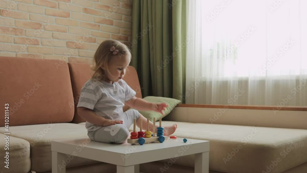 Little girl playing wooden education games on the table. Sorting rainbow wheels. Medium shot. Little girl playing wooden education games on the table. Sorting rainbow wheels. Medium shot.