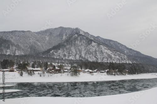 Landscape with snow covered mountains, village and river