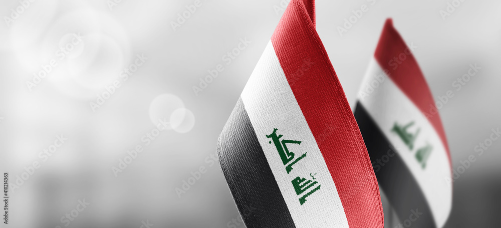 Small national flags of the Iraq on a light blurry background - obrazy, fototapety, plakaty 