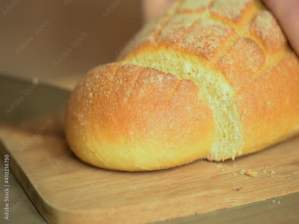 A man cuts bread with a serrated knife. A man cuts bread with a serrated knife.