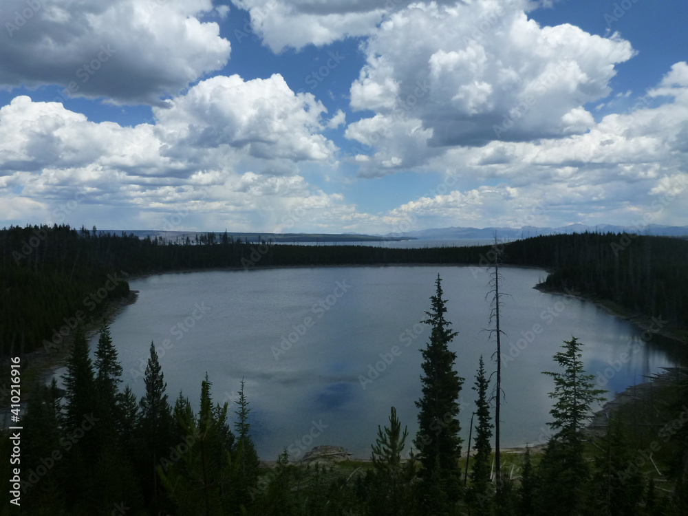 View of a small lake surrounded by trees at Yellowstone National Park, on a. cloudy day