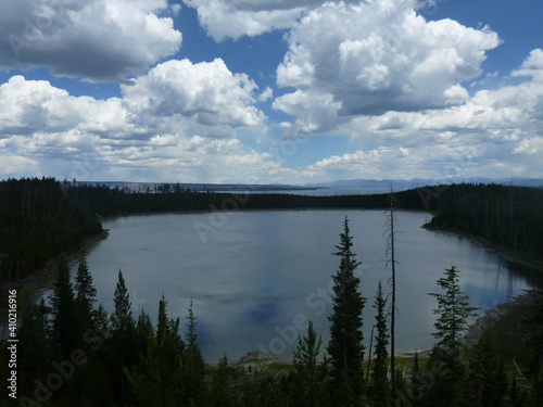 View of a small lake surrounded by trees at Yellowstone National Park, on a. cloudy day