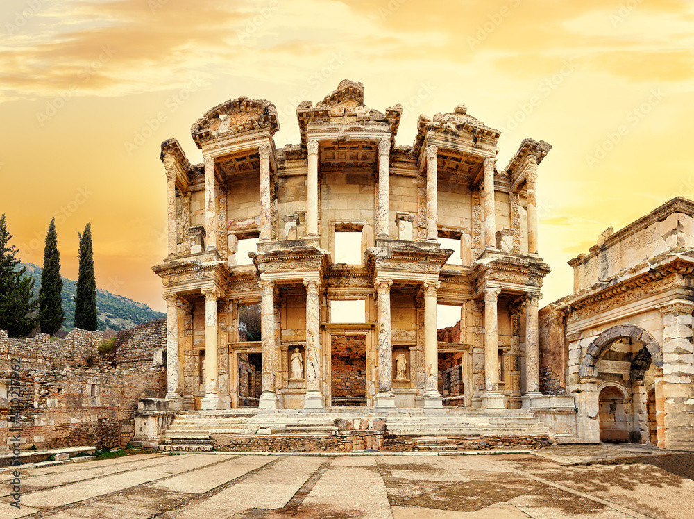 Facade of library of Celsus in Ephesus under yellow sunset sky