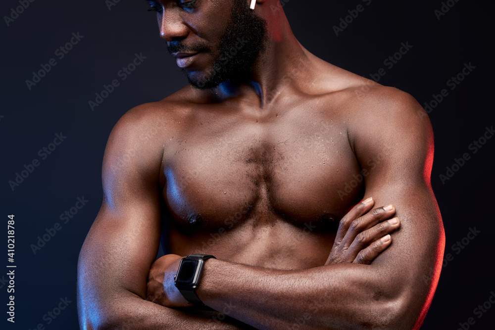 Fototapeta premium shirtless muscular sportsman standing with crossed arms, looking down. bodybuilding, weightlifting concept. isolated on black background