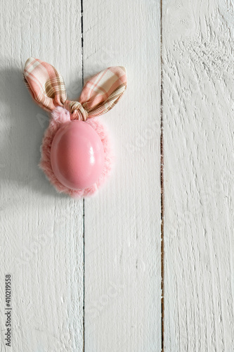 Pink easter egg with bunny ears on white wooden background. Minimal, creative concept. Flat Lay.