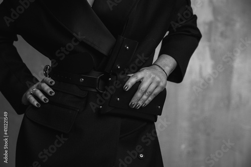 A business woman in a strict black coat and with a clutch in her hands goes out into the city