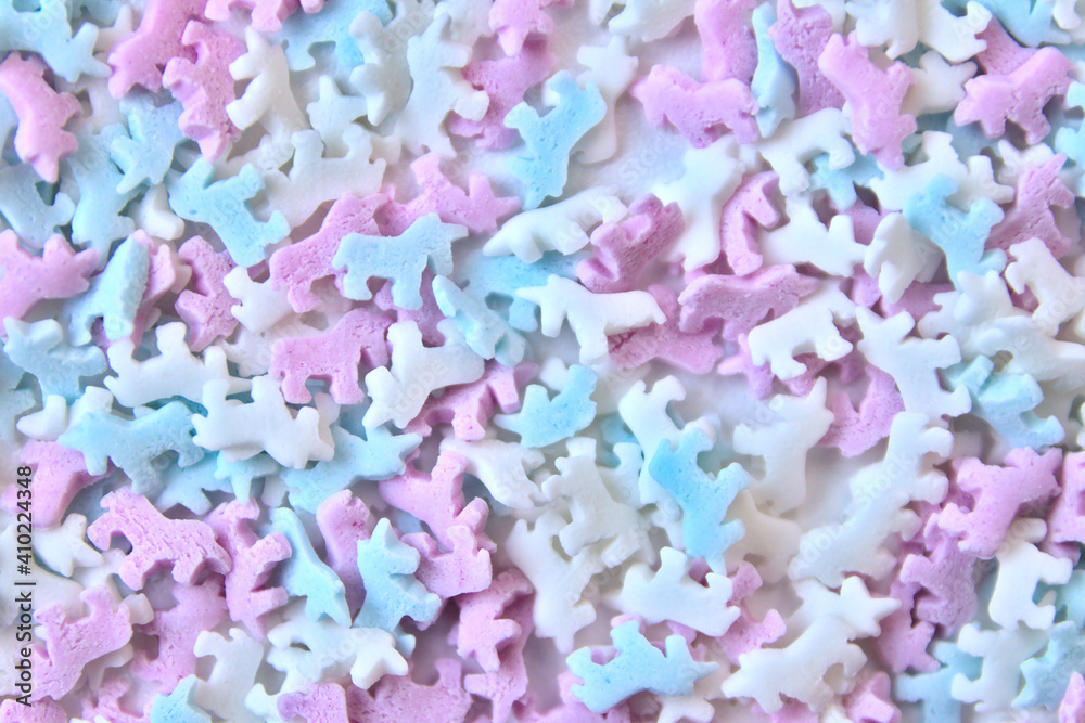 Obraz premium Delicious sugar candy unicorns in red, blue and white as sweet cake decoration and birthday topping with little horses and unicorn sprinkles as delicious background for confection frosting of donuts