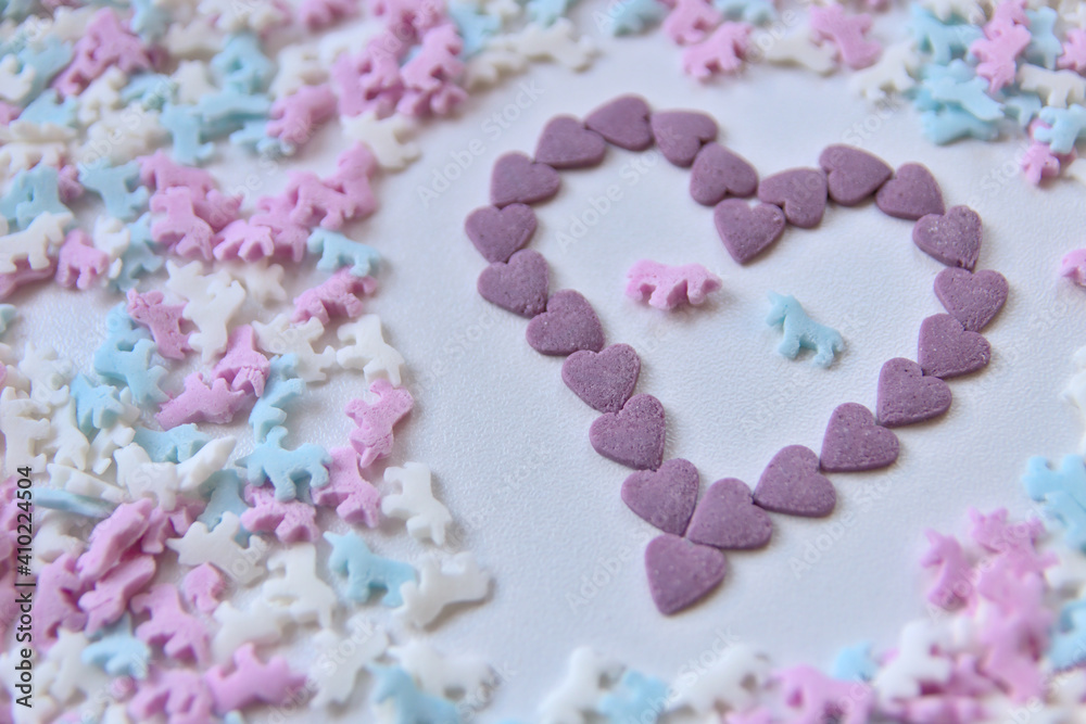 Delicious sugar candy unicorns in red, blue and white as sweet cake decoration and birthday topping with little horses and unicorn sprinkles show love for confection frosting of hearts