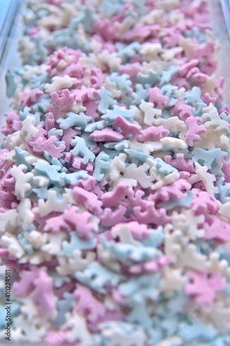 Delicious sugar candy unicorns in red, blue and white as sweet cake decoration and birthday topping with little horses and unicorn sprinkles as delicious background for confection frosting of donuts