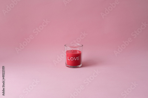 A single red candle on pink backgroud. Valentine's day.