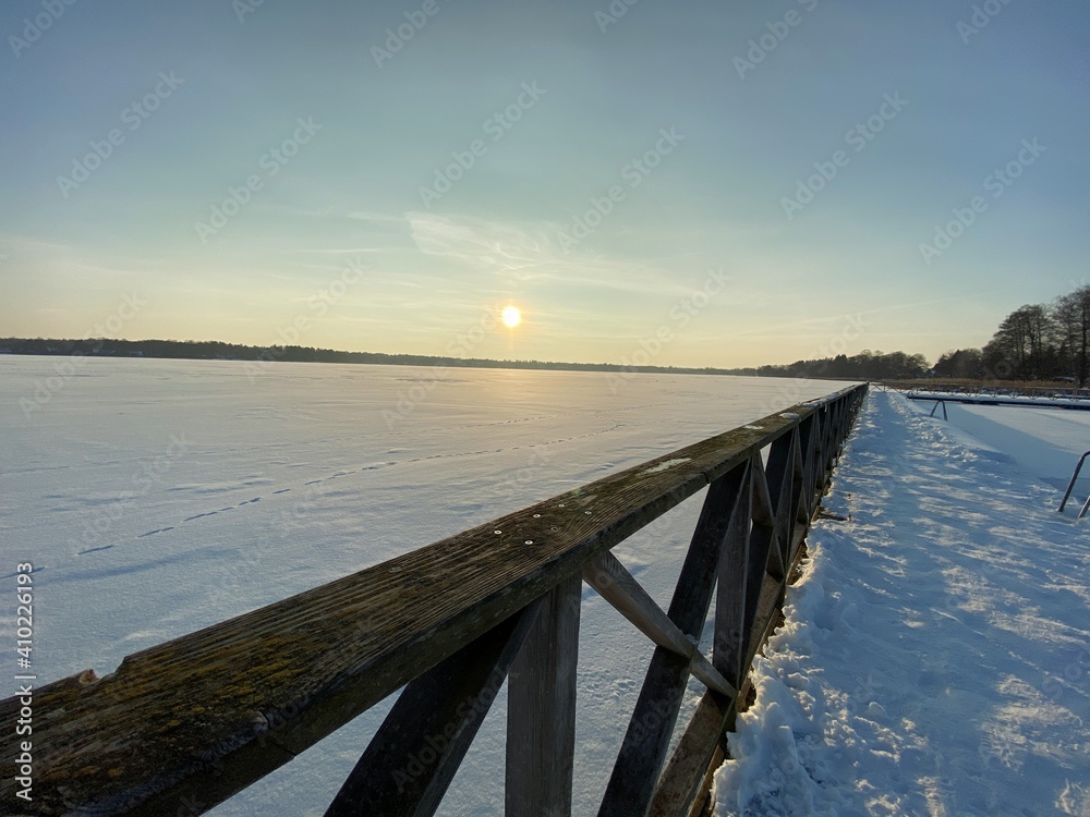 View of the frozen Białe Lake near Włodawa with wooden decks a lot of snow just before sunset golden hour