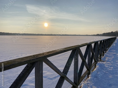 View of the frozen Bia  e Lake near W  odawa with wooden decks a lot of snow just before sunset golden hour