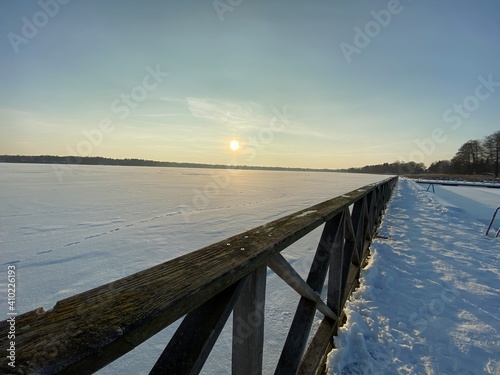 View of the frozen Białe Lake near Włodawa with wooden decks a lot of snow just before sunset golden hour © Józef