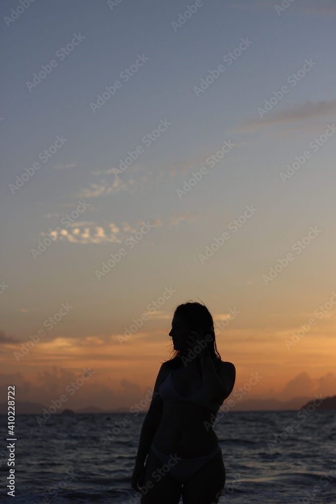 Woman posing at sunset on a beach in a swimsuit
