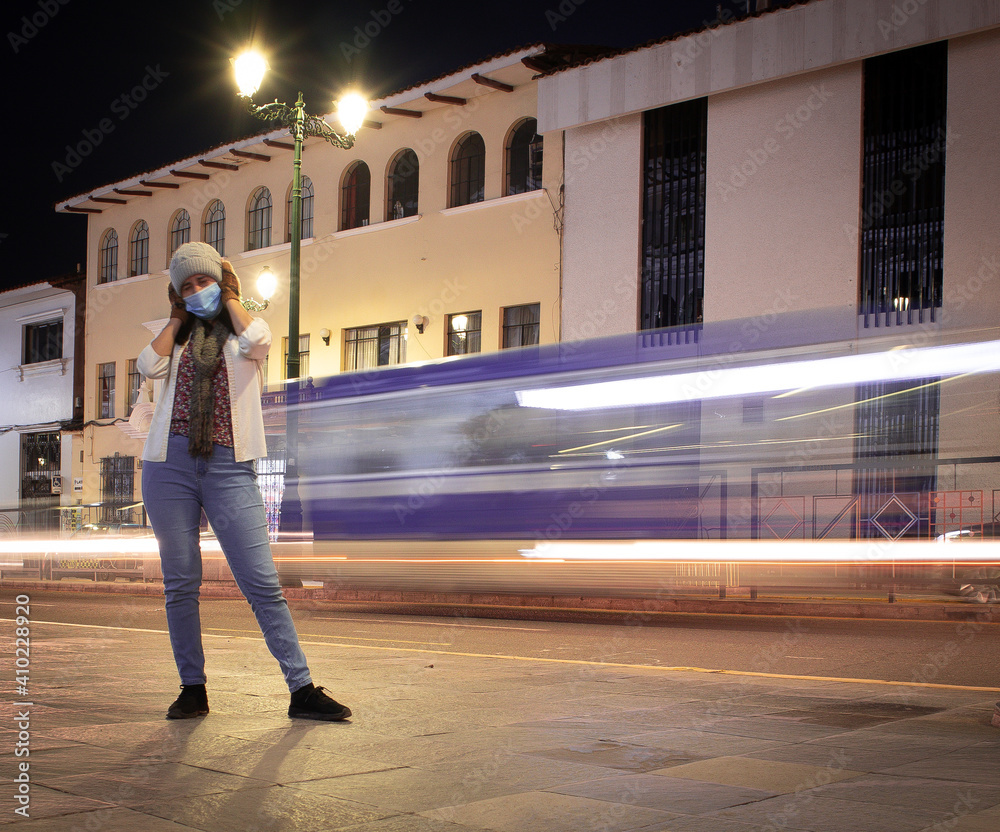 Person standing in the street with many lights, eyes closed, wearing a