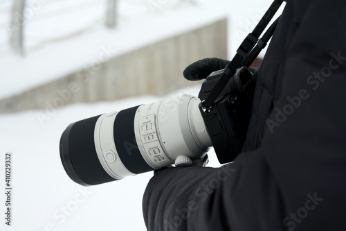  A cut-off image of a man with a zoom telephoto lens in his hand. Copy space.