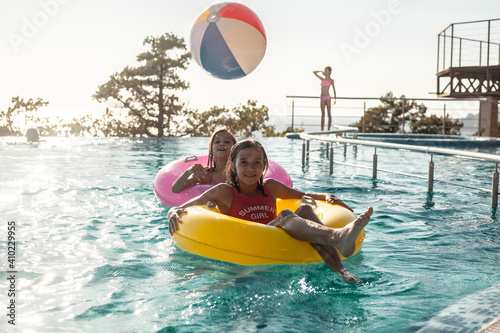 Children resting in swimming pool together. Kids swim, dive, leisure and playing infatable ball in pool at suumer vacation photo