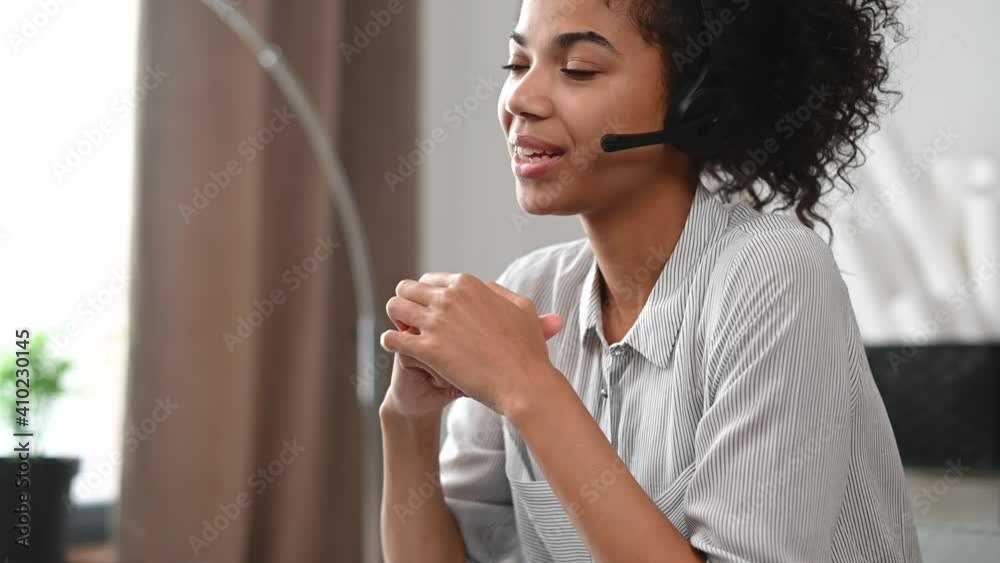 Close-up of an African businesswoman in a headset holding the microphone and takes a call, an attentive multiracial female customer service representative responding to the customer inquiry