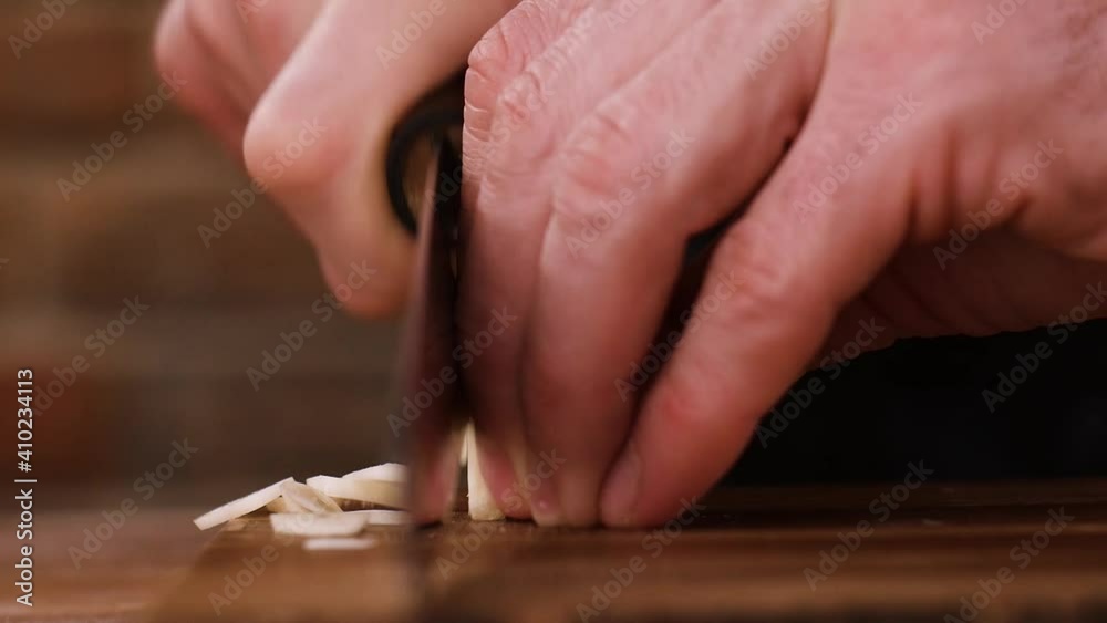 Chef slicing garlic cloves on a wooden board. Chef slicing garlic cloves on a wooden board.
