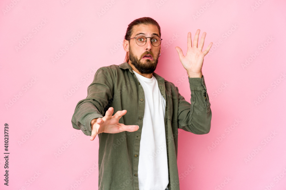 Young man with long hair look being shocked due to an imminent danger Young man with long hair look being shocked due to an imminent danger