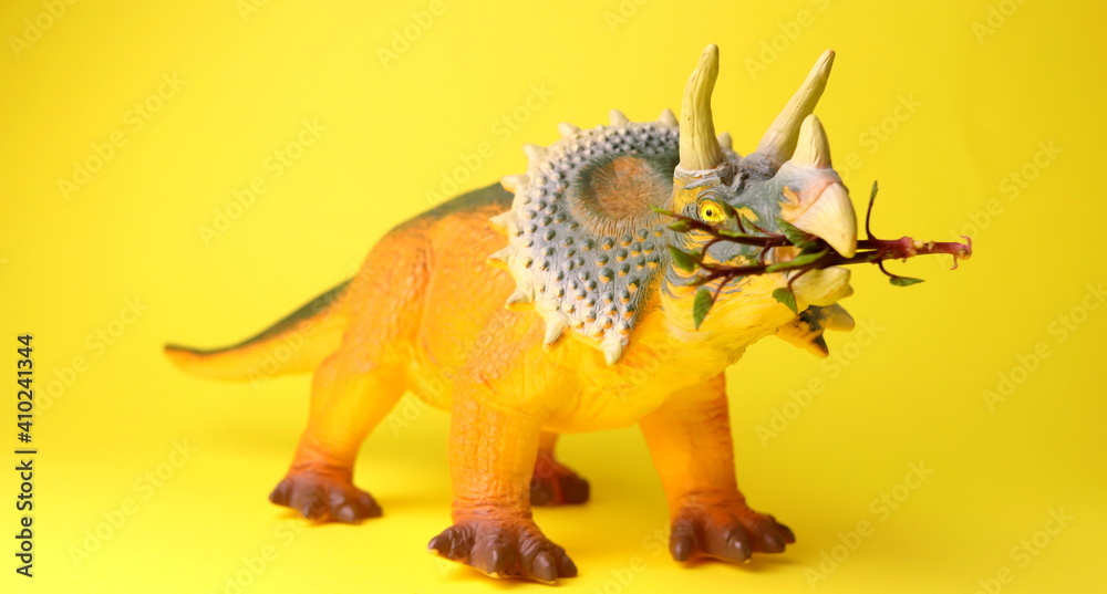toy in the shape of a dinosaur on a yellow background close-up selective focus. toy in the shape of a dinosaur on a yellow background close-up selective focus.